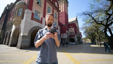 Man Using Smartphone on Historic City Street. Subotica, Serbia Stock Footage 308636399