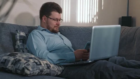 Man using smartphone at home sitting with laptop Stock Footage 340207869
