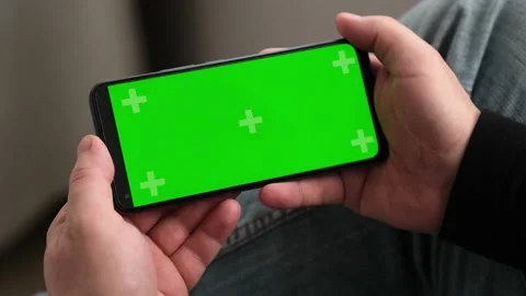Man using smartphone in horizontal position with green mockup screen. Chroma key Video stock 237452384