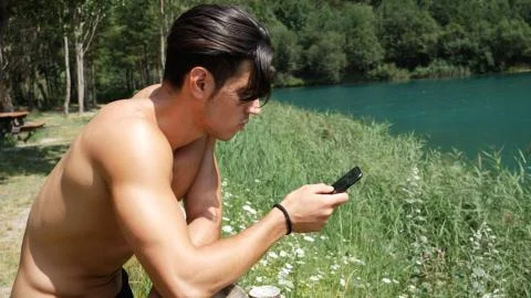 Man using smartphone at lake Stock Photos