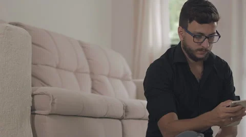 A man using smartphone on the living room floor to access the internet 動画素材 59329045