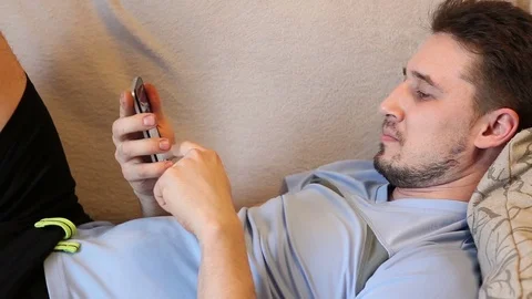 Man using a smartphone, lying on the couch Stock Footage 72582025