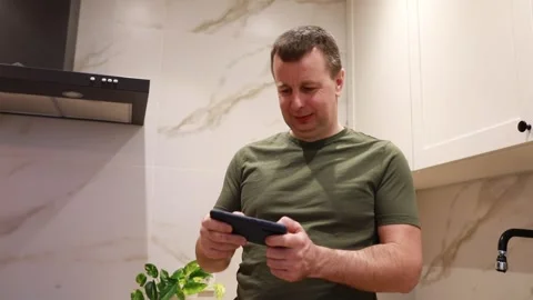 Man Using Smartphone in Modern Kitchen During Evening Hours Stock Footage 273627176