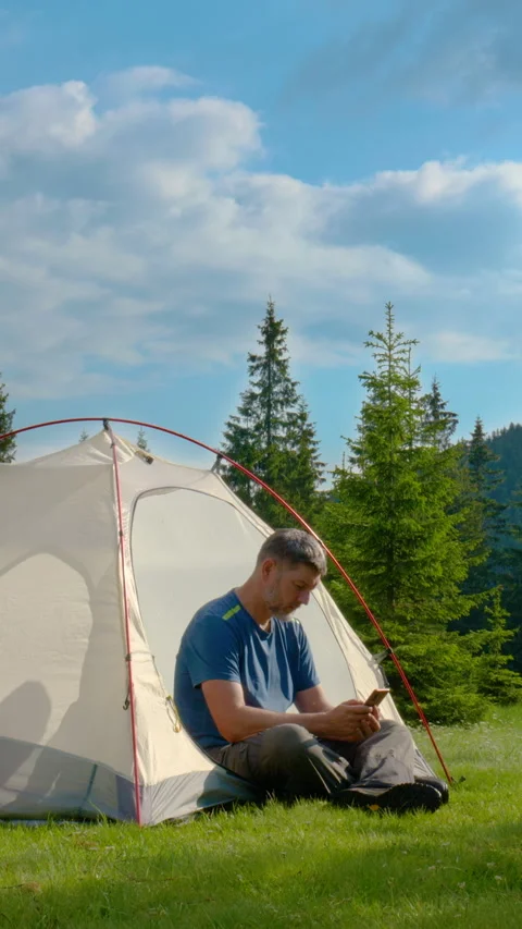 Man Using Smartphone Near Tent During Mountain Camping Trip Stock Footage 335439592