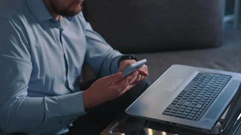 Man using smartphone next to laptop during remote work Stock Footage 340203550