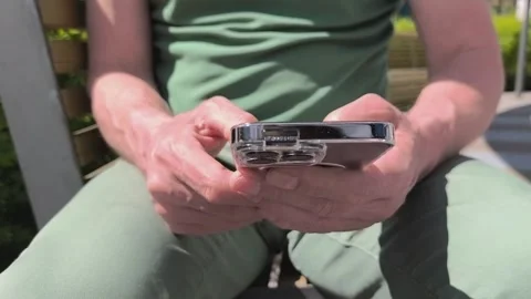 Man using smartphone outdoors in bright sunlight. Hands hold a mobile devic.. Stock Footage 336975269