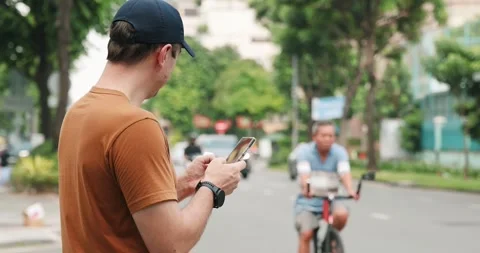 Man using smartphone outdoors on busy city street, wearing casual Stock Footage 322061661