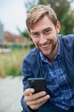 Man using smartphone outdoors, smiling, portrait Stock Photos