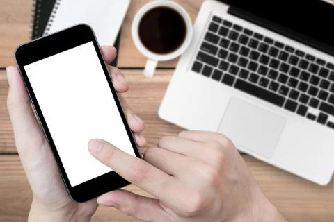 Man using smartphone over the office desk, top view. Stock Photos