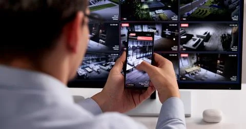 Man Using Smartphone For Real-Time CCTV Surveillance And Security Alerts Stock Photos
