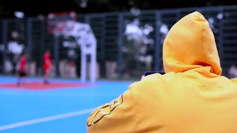 Man using smartphone resting on basketball court modern sports ground with 스톡 동영상 136180844