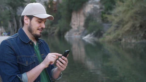 Man using a smartphone by the river Stock Footage 265120715