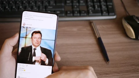 Man Using Smartphone With To Scroll Instagram Profile Of Elon Musk, News. Tes Stock Footage 137160651