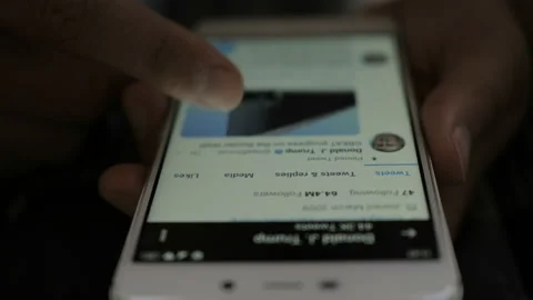 Man Using Smartphone With To Scroll Twitter Profile Of President Of USA Donal Видео 117981301