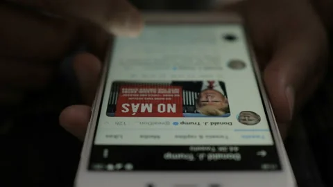 Man Using Smartphone With To Scroll Twitter Profile Of President Of USA Donal Stock Footage 122925174