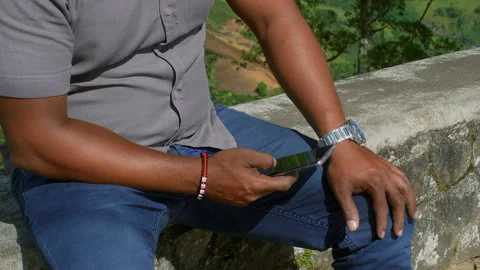 Man using smartphone sitting on concrete wall in the hills Stock Footage 311424634