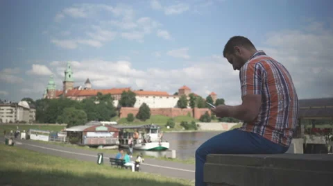 Man using smartphone sitting on wall by the river Video stock 52696948