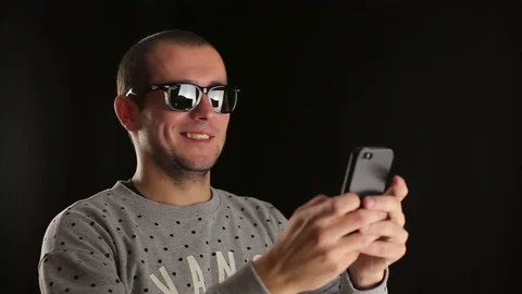 Man using smartphone smiling and typing message in black sudio indoors Stock Footage 70520611