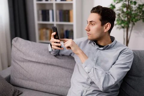 Man using smartphone on sofa Stock Photos