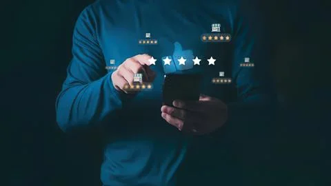 Man using smartphone with star rating icons floating above Stock Photos