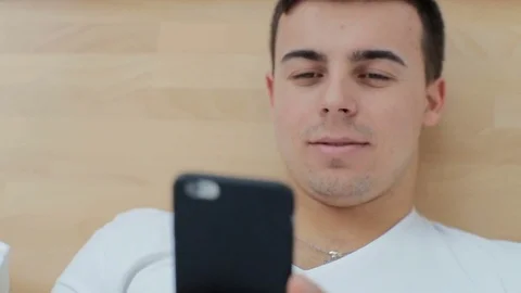 Man using smartphone touchscreen in bed at home Stock Footage 73751841