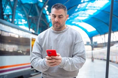 Man using smartphone at train station while traveling Stock-Fotos