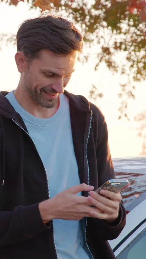Man using smartphone to unlock carsharing service, standing beside vehicle Stock Footage 318475201