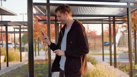 Man using smartphone in urban park setting, managing daily tasks with focus Stock Footage 317702449