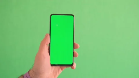 Man Using Smartphone in Vertical Mode with Green Mock-up Screen, Doing Swiping Video stock 241934092