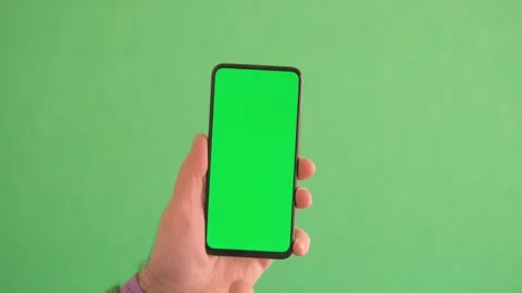 Man Using Smartphone in Vertical Mode with Green Mock-up Screen, Doing Swiping Stock Footage 242187080