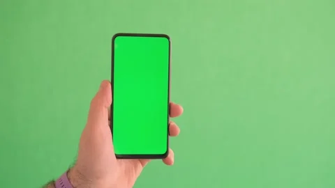 Man Using Smartphone in Vertical Mode with Green Mock-up Screen, Doing Swiping Stock Footage 244650125