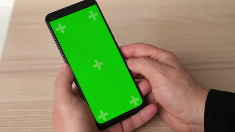 Man using smartphone in vertical position with green mock-up screen on table Video stock 237872935