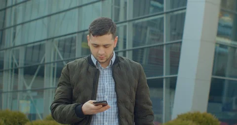 Man using a smartphone voice recording function online walking on a city street 스톡 동영상 127694470