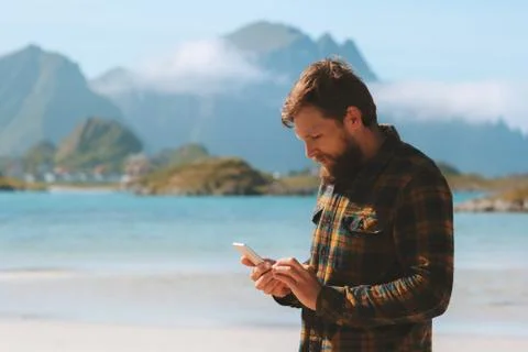 Man using smartphone walking on beach modern technology influencer freelancer Stock Photos