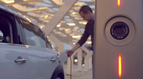 Man using the smartphone while charging its electric car Stock Footage 62226435