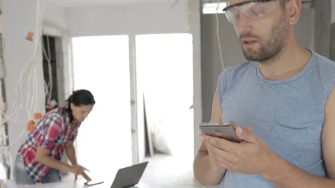 Man using smartphone while counting something and woman checking project, steady Stock Footage 78627353