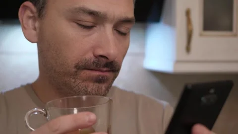 Man Using Smartphone While Enjoying a Drink at Home Stock Footage 312530867