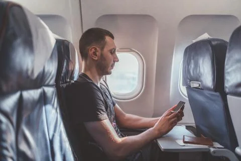 Man using a smartphone while flying in a plane. 写真素材
