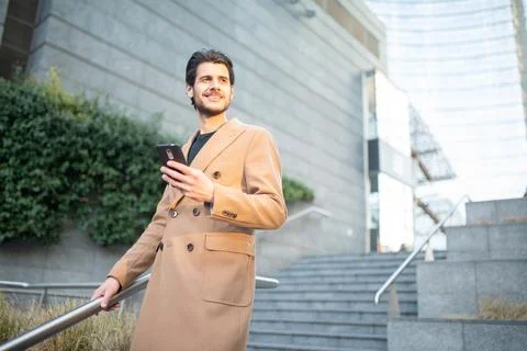 Man using a smartphone while leaning on stairs outdoor Stock Photos