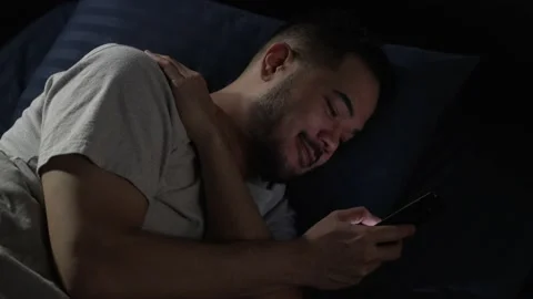 Man using smartphone while lying in bed at night Stock Footage 167941805