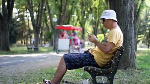 Man using  smartphone while relaxing in the park Vídeos de archivo 112359213