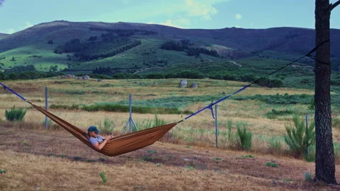 Man using smartphone while relaxing in mountain hammock Vídeos de archivo 343687885