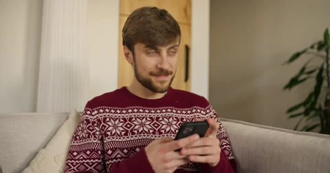 Man using smartphone while sitting on sofa in cozy living room Stock Footage 303900317