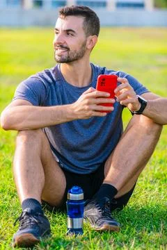Man using smartphone while sitting on grass in outdoor park.Vertical Stock-Fotos