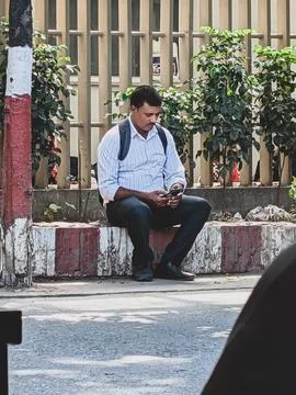 Man using smartphone while sitting outdoors Stock Photos