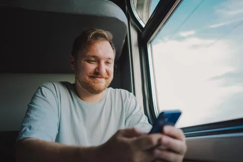 A man using a smartphone while traveling by Railway train Stock Photos