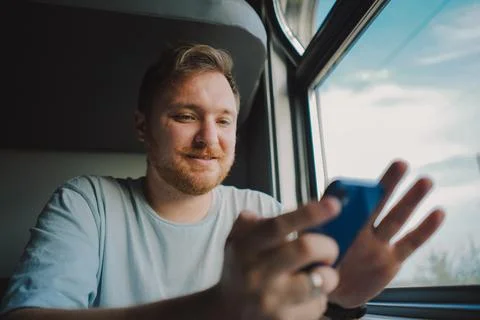 A man using a smartphone while traveling by Railway train Stock Photos