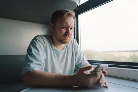 A man using a smartphone while traveling by Railway train Stock Photos