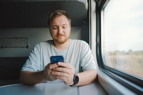 A man using a smartphone while traveling by Railway train Foto stock