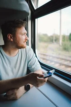 A man using a smartphone while traveling by Railway train Stock Photos